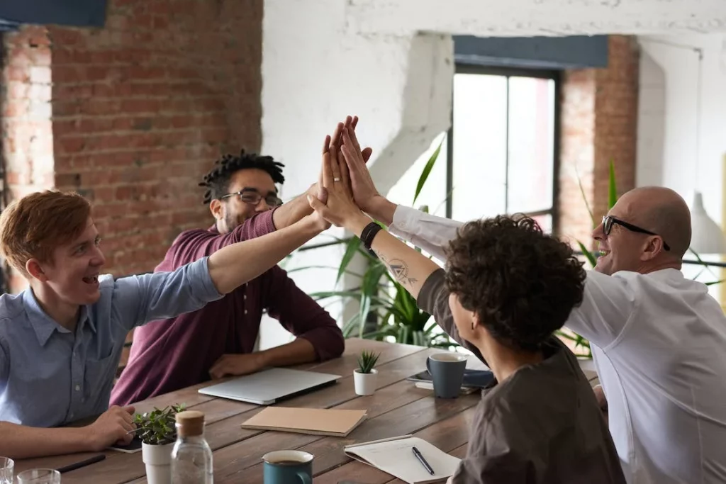 Equipo de trabajo celebrando juntos el éxito en un curso de inglés bonificado para empresas.